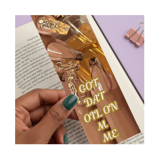 Gold nail clippers with a decorative charm held by a hand, on a book background.