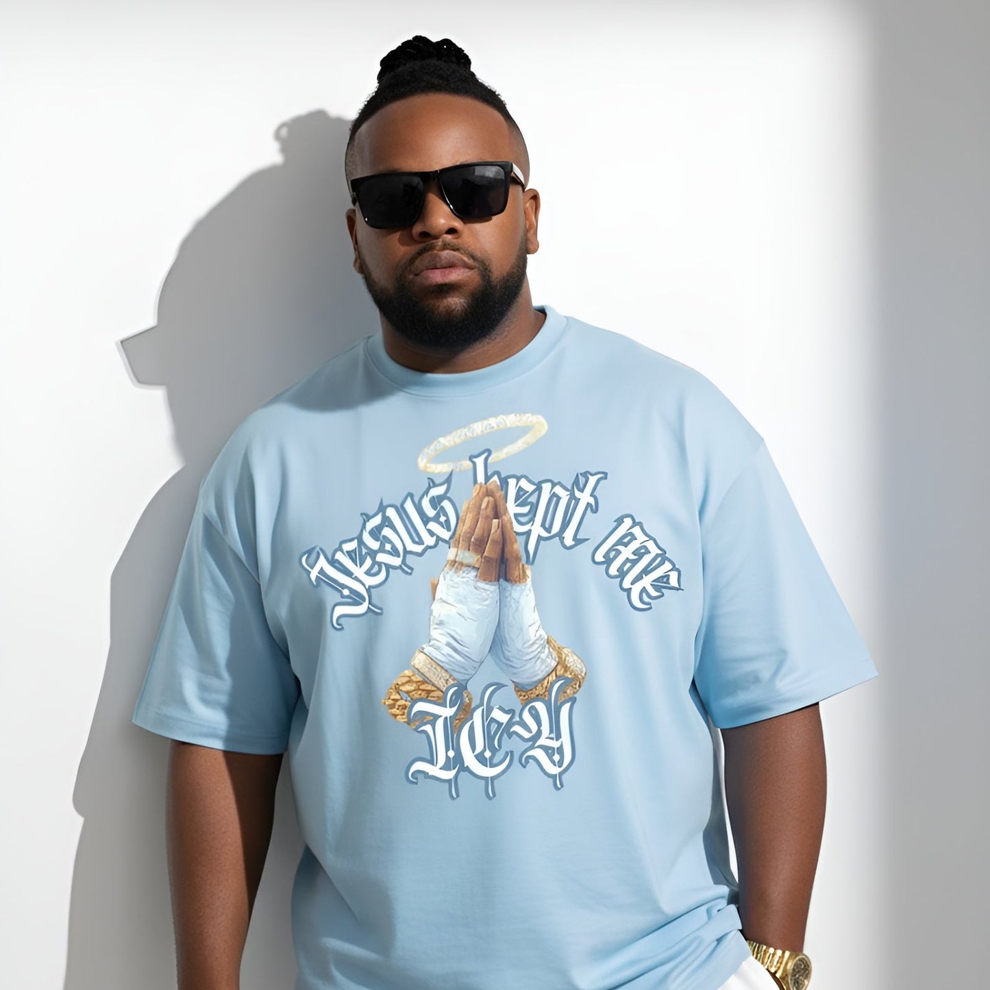 Man wearing a light blue t-shirt with graphic design and text, standing against a white background.