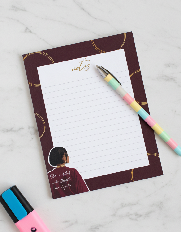 Notepad with a design of a woman and the word 'notes' on a marble surface with a pen and markers.