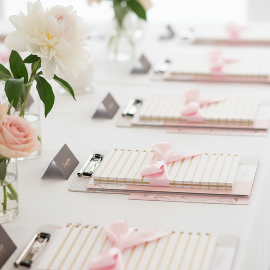 Table with stationery items and flowers on a white surface
