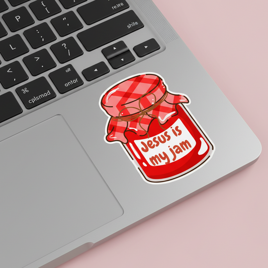 Sticker on a laptop with 'Jesus is my jam' text on a red jar design.