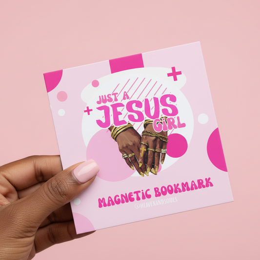Pink magnetic bookmark with 'Just a Jesus Girl' text and hands holding a cross, held by a hand on a pink background.