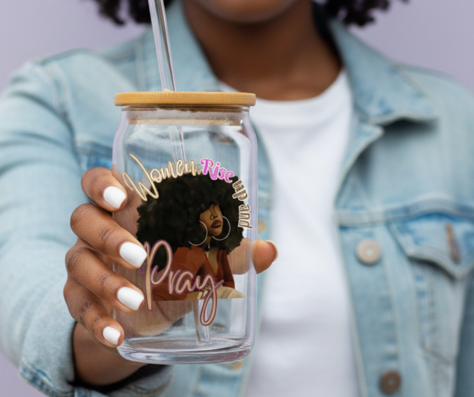 Person holding a clear glass tumbler with a wooden lid, featuring an illustration of a woman with text on it.