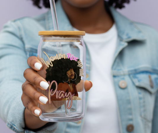Person holding a clear glass tumbler with a wooden lid, featuring an illustration of a woman with text on it.